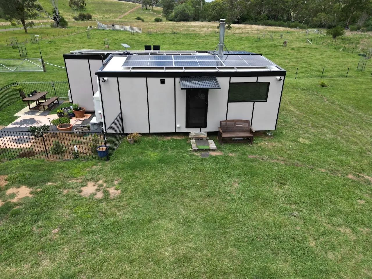 Aerial photograph of a MicroHome sited and levelled on a cleared pad on a grassy hillside.