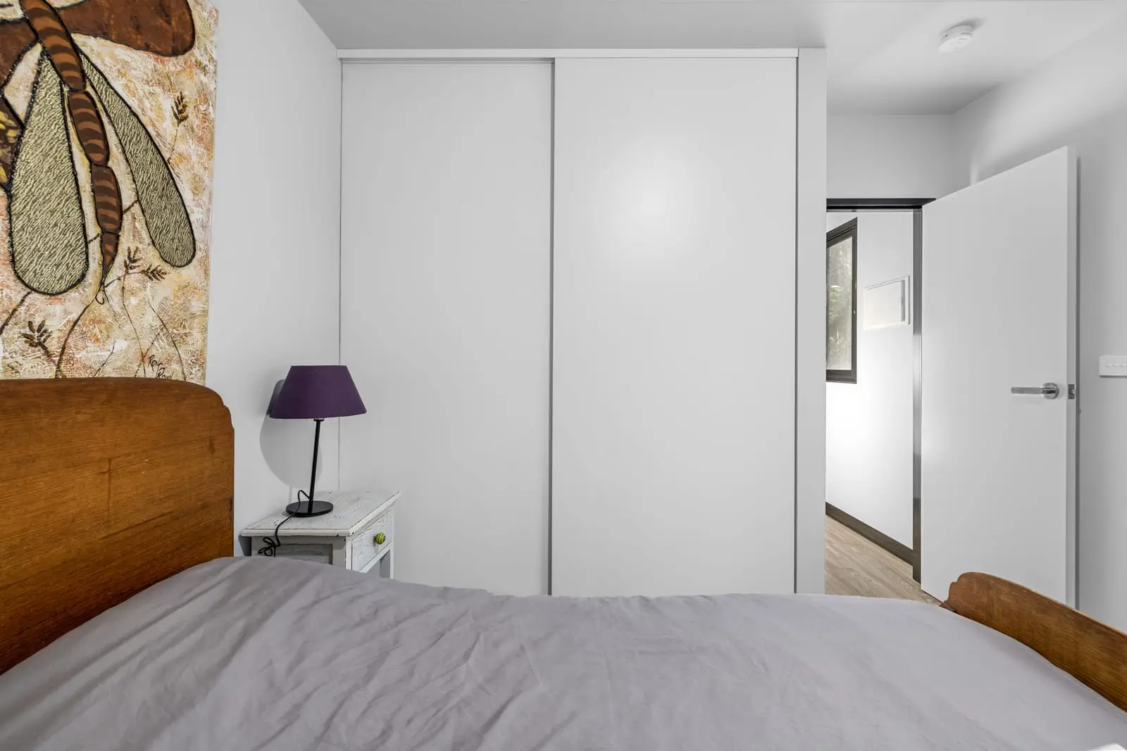 Built-in mirrored robes along a MicroHome bedroom wall, with the door through to the rest of the home.