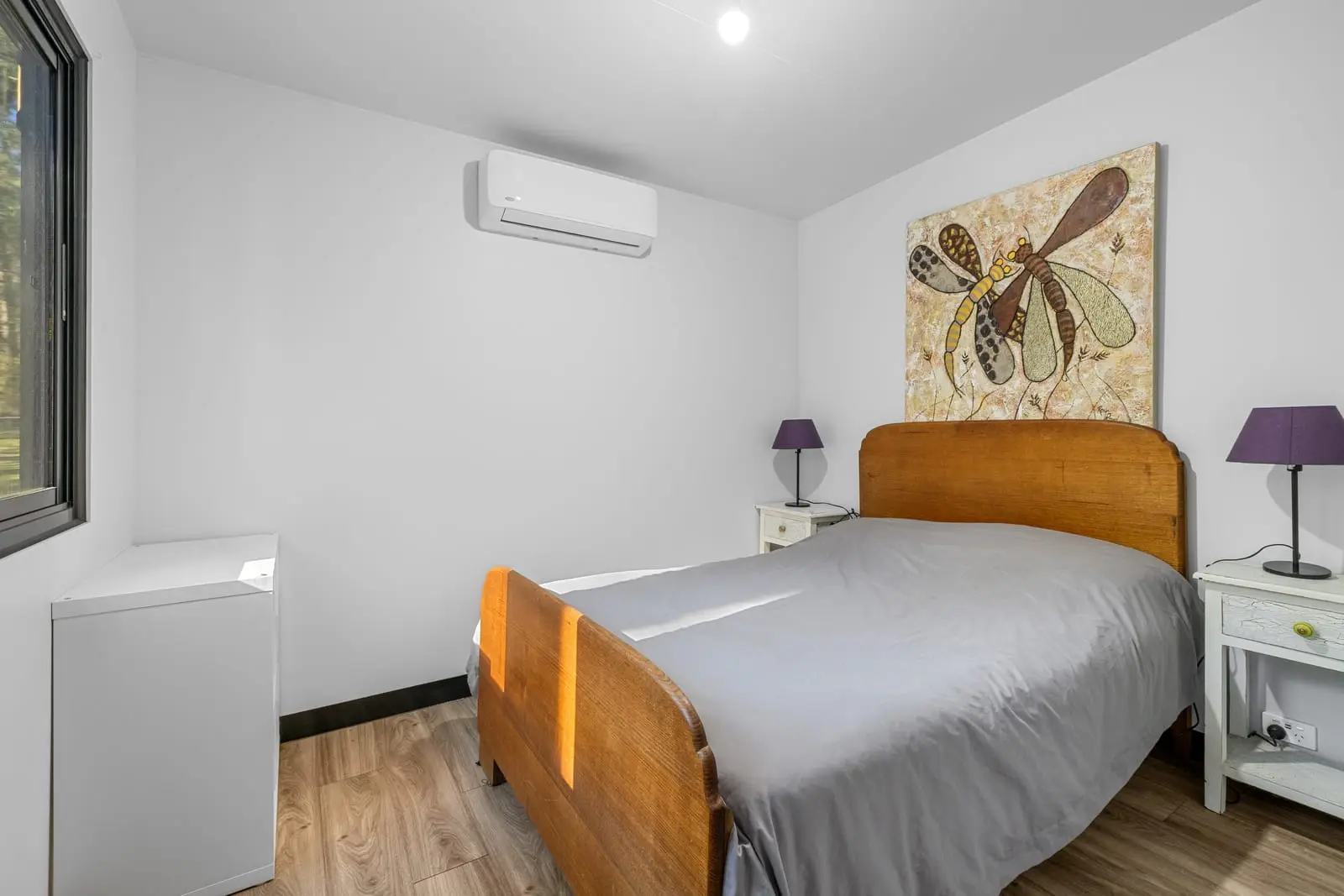 A MicroHome bedroom with a double bed, bedside tables and a reverse-cycle split system.