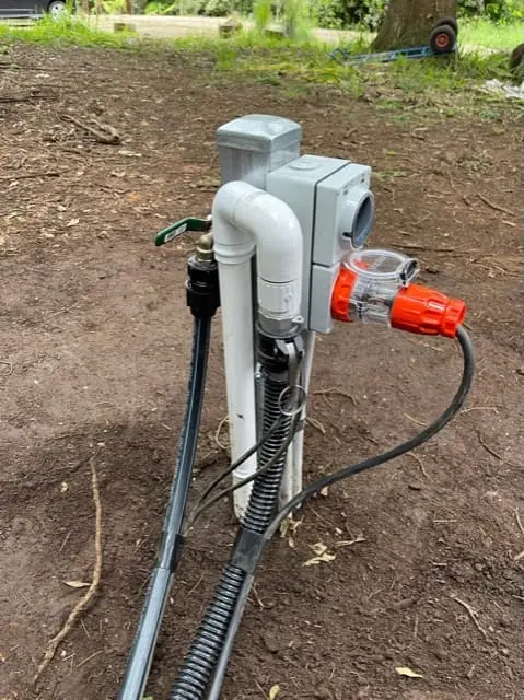 The services connection post beside a sited MicroHome, with power and water connected.