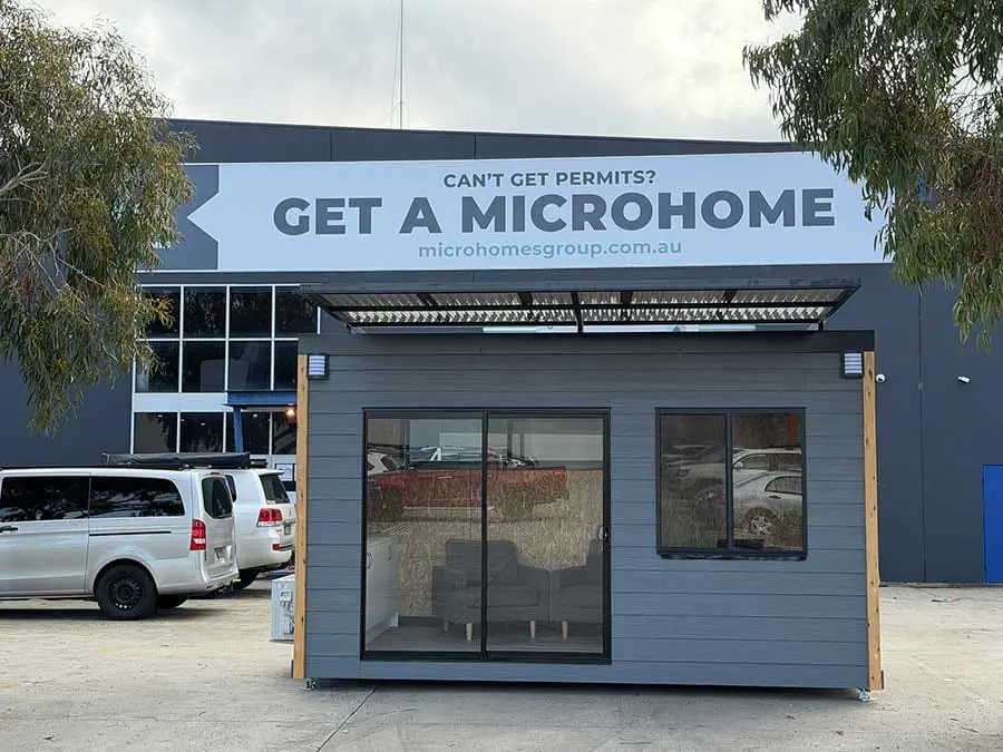 The MicroHomes Group factory in Melbourne, with one of our units parked out the front under a banner reading “Can’t get permits? Get a MicroHome.”