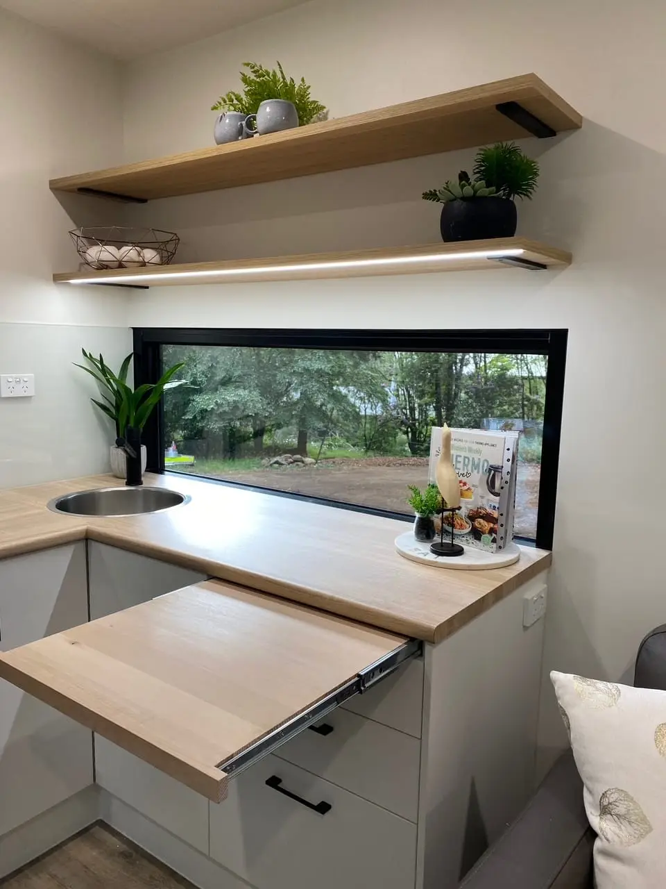 Kitchen bench and open shelving in a MicroHome, with a window over the sink.
