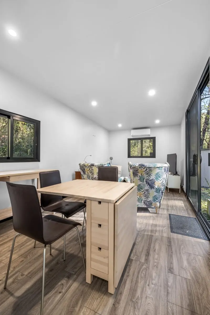 A dining table and chairs in a MicroHome living zone, beside the sliding entry door.