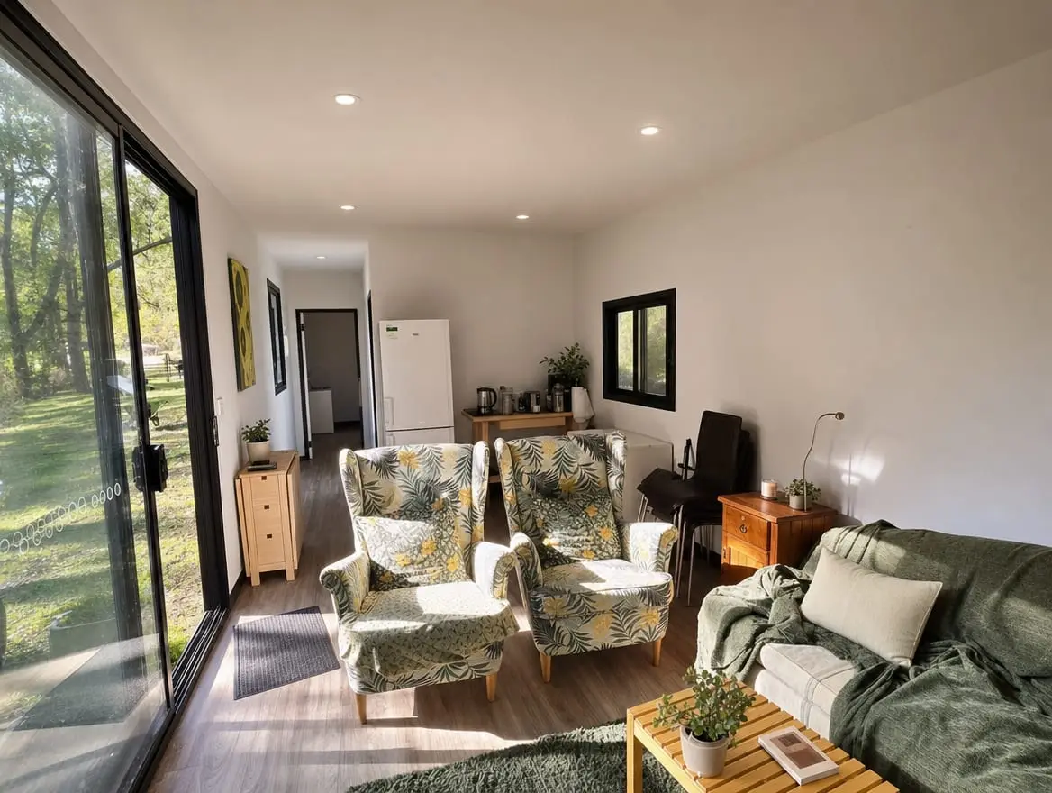 A wide, open-plan MicroHome interior with full-size furniture and large windows to the bush.