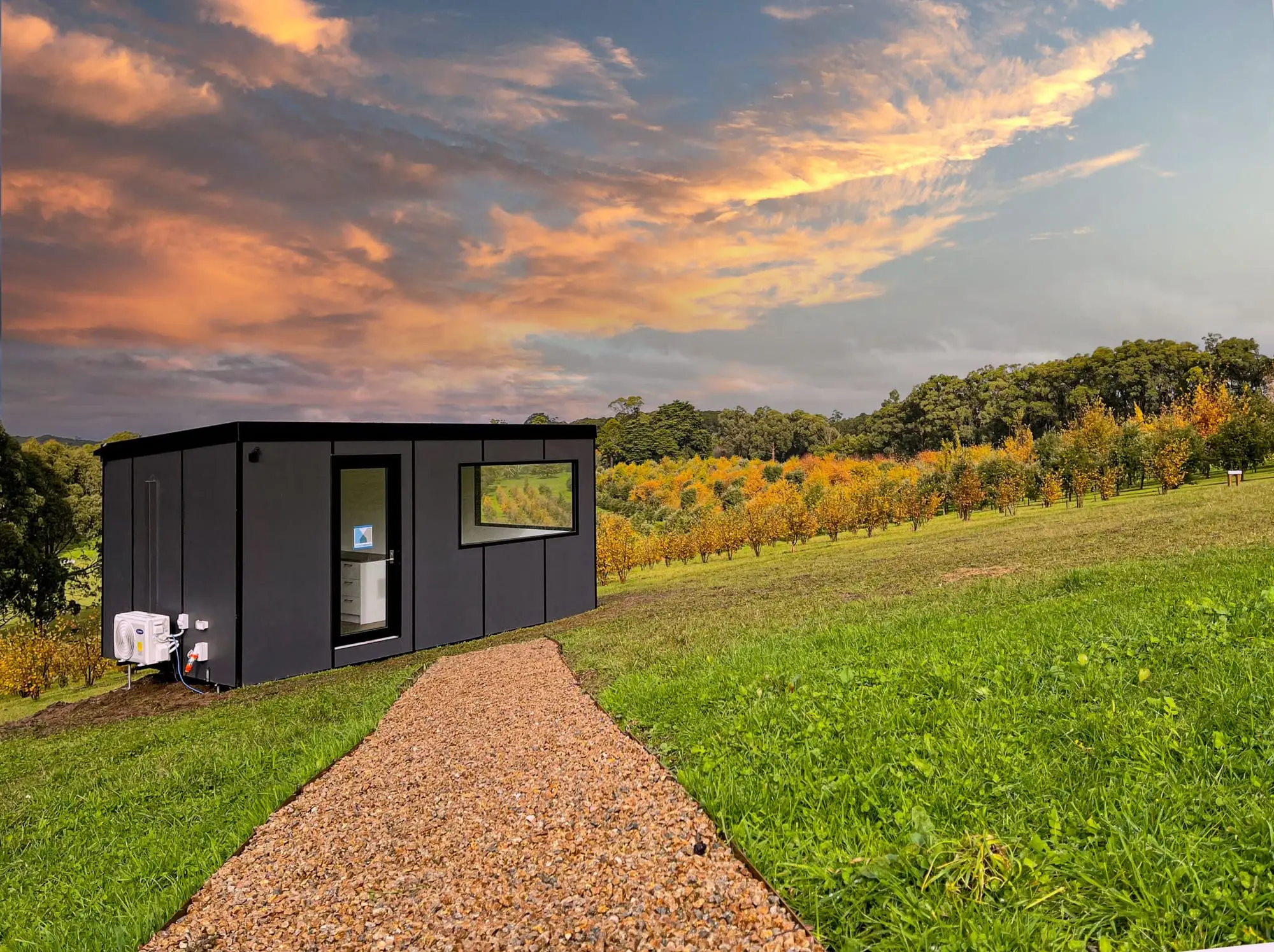 An Urban Multispace sited on a grassy rise above an orchard at dusk.