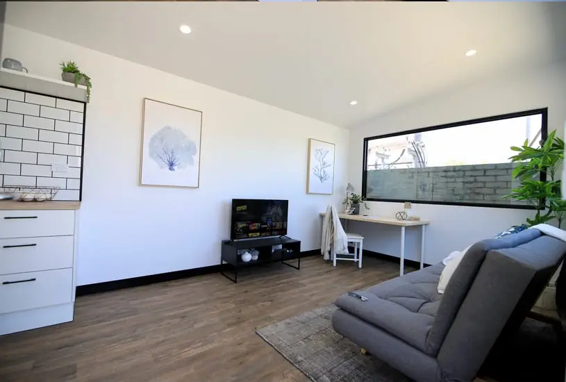 Inside an Urban Multispace fitted out as a home office, with a desk under a wide window, a screen and lounge seating.