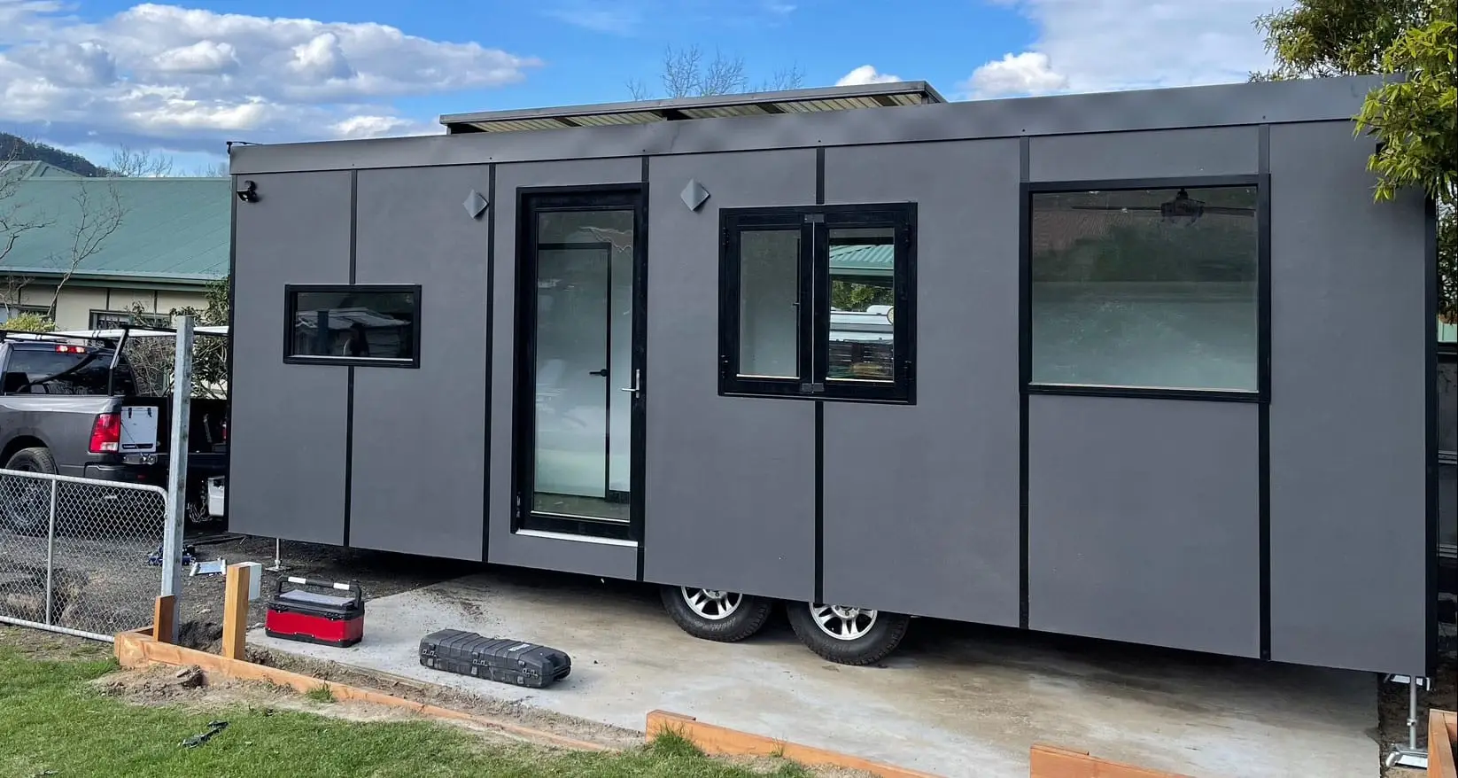 A completed MicroHome standing on its own registered chassis and wheels in the yard.