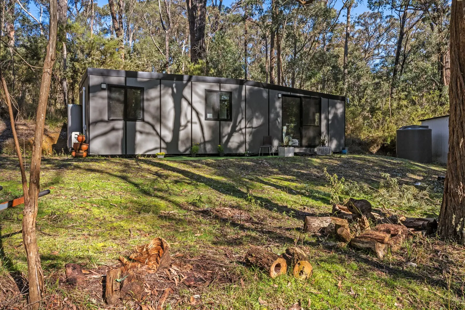 The same MicroHome seen along its full length across a grassy bush clearing.