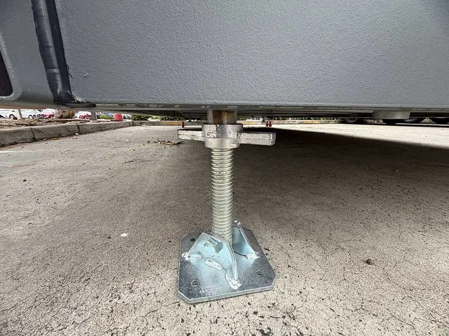 Close-up of an adjustable levelling leg screwed down onto its footing plate beneath a Backyard Pod.
