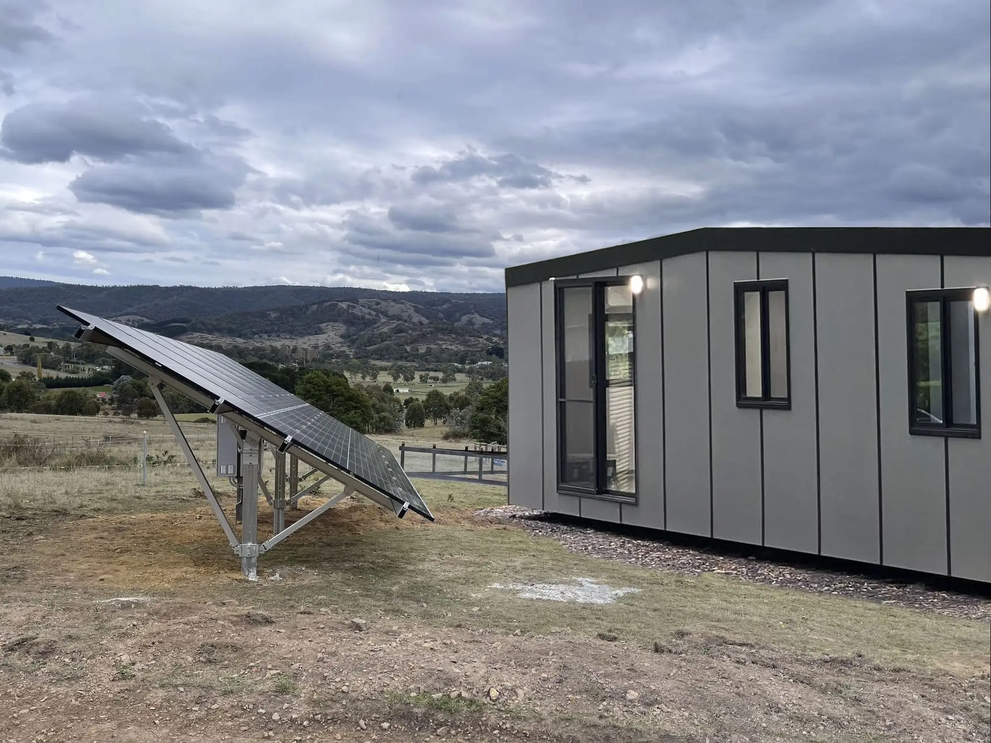 A ground-mounted solar array on a rural block, supplying an off-grid MicroHome.