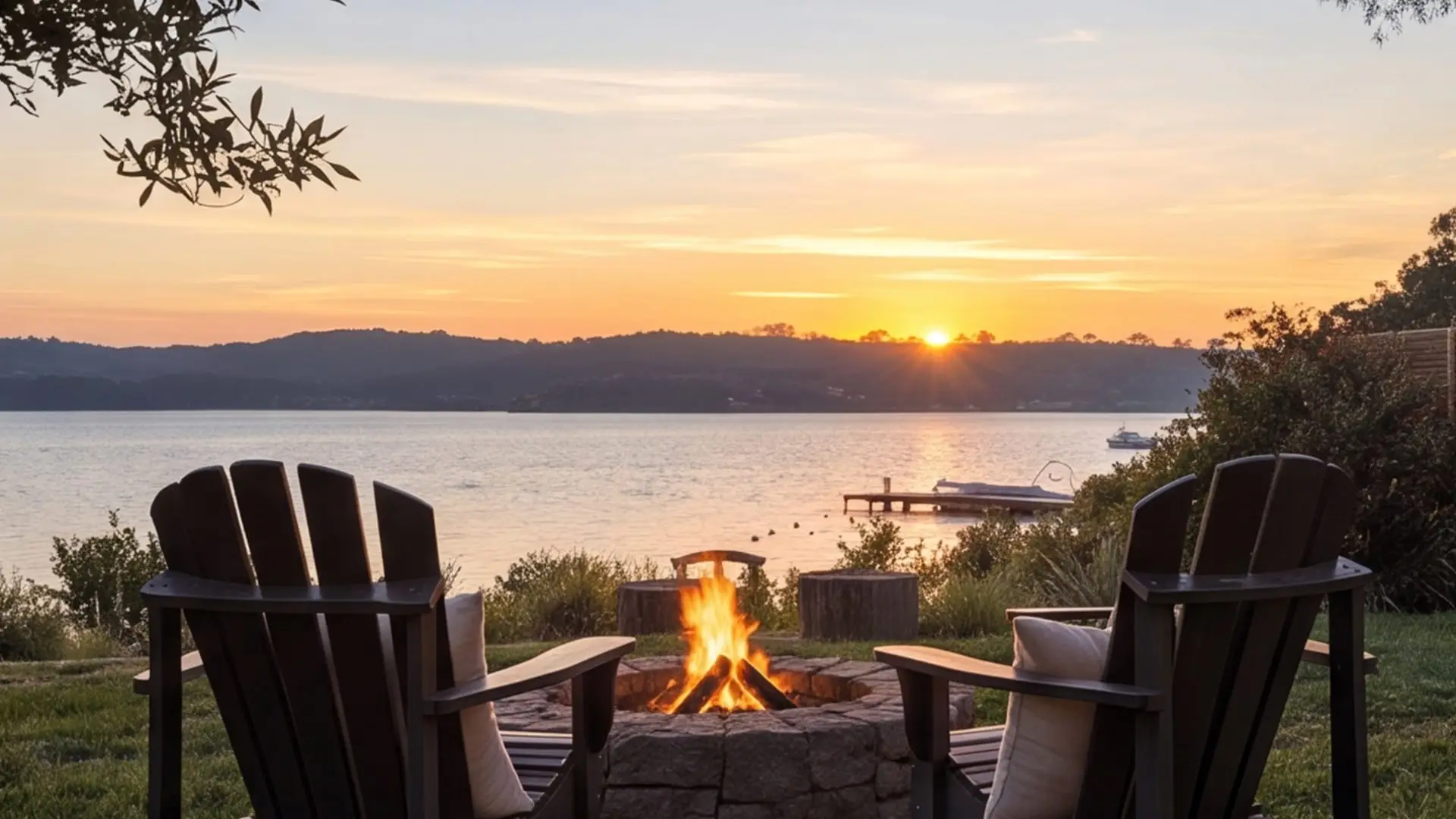 A MicroHome at sunset with a fire pit and outdoor chairs by the water.