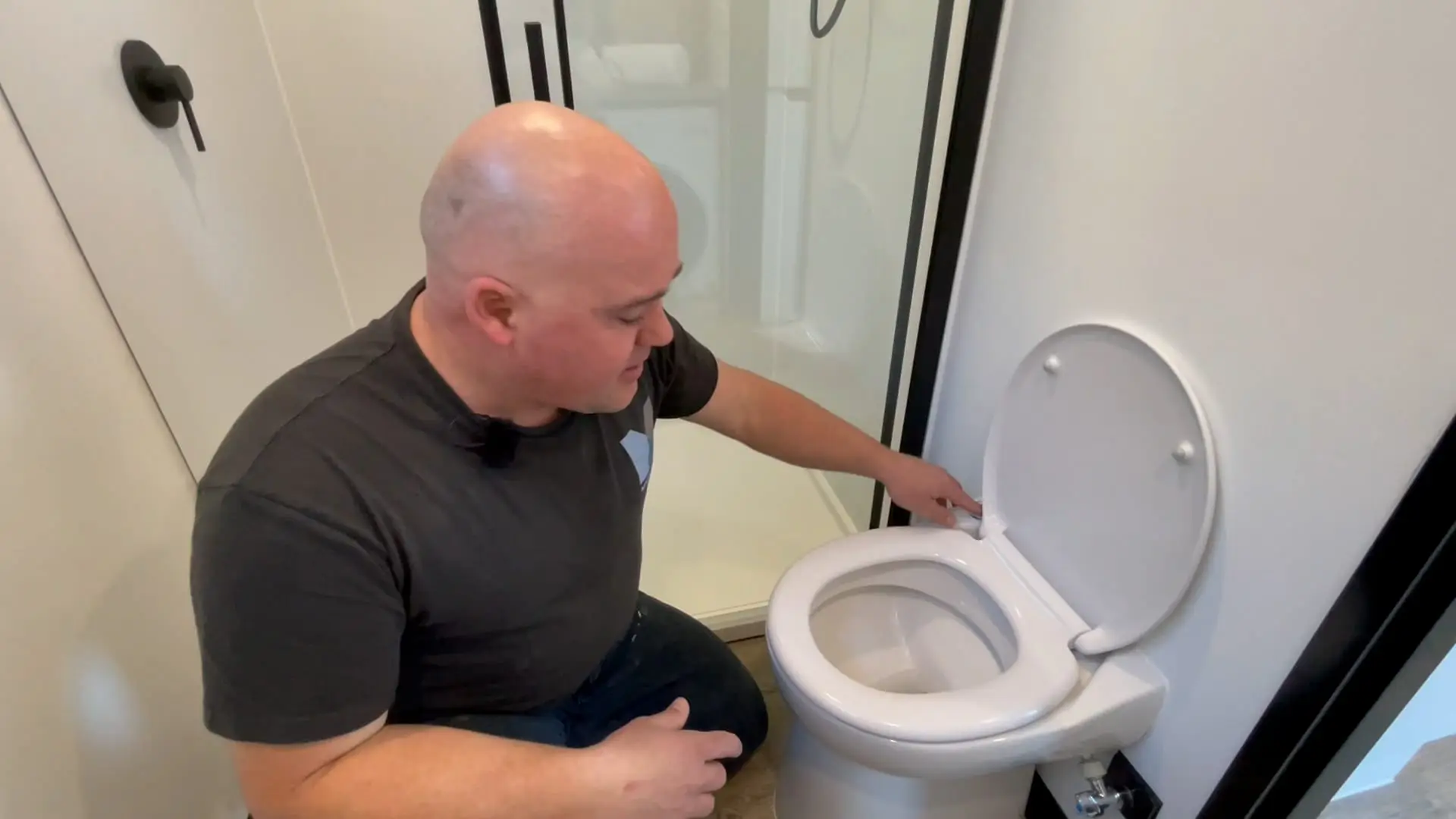 A MicroHomes team member flushing the toilet in a finished MicroHome bathroom.
