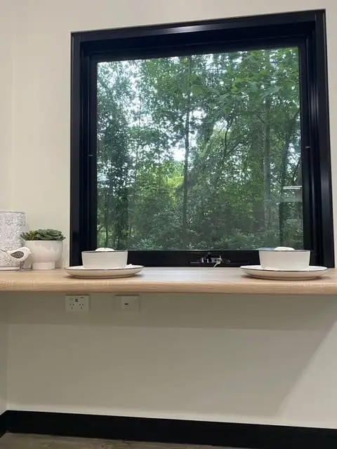 A MicroHome window over a timber bench, with bowls and a power point below the sill.