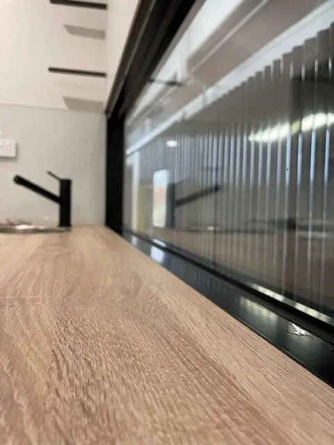 The full length of a MicroHome interior, timber-look floor and a run of windows down one side.